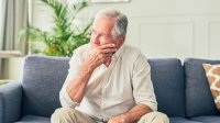 Man zorgelijk op de bank in zijn woonkamer