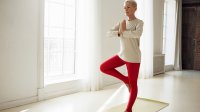 Vrouw doet aan yoga, staat in de boomhouding