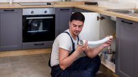 Werkende man is bezig afvoer van kraan te vervangen