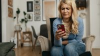Vrouw is boos, kijkt op haar telefoon in de woonkamer