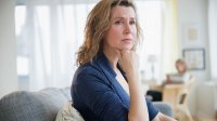Vrouw zit op de bank kijkt zorgelijk
