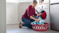 Vrouw doet kleding in de wasmachine