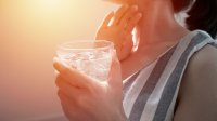 Vrouw drinkt glas water met ijsblokjes in de warmte