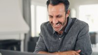 Man kijkt thuis lachend op laptop