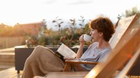 Vrouw drinkt een kop koffie in de ochtendzon
