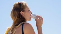 Vrouw drinkt in de warme zon een blikje fris