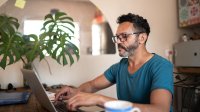 Man is thuis bezig met zijn laptop