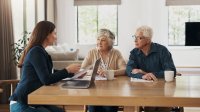 Makelaar in gesprek met senior stel aan de keukentafel