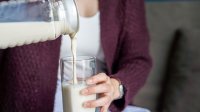 Vrouw schenkt melk in een groot glas
