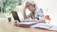 Vrouw achter laptop met zorgelijke blik