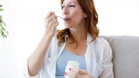 Vrouw eet crème fraîche op de bank