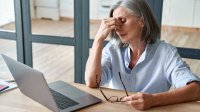 vrouw met vermoeide ogen achter laptop