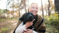 vrolijke vrouw met hond in bos