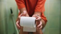 Vrouw op toilet met toiletrol