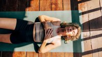 vrouw doet ademhalingsoefeningen op yogamat