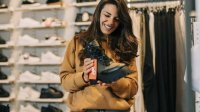 Jonge vrouw koopt schoenen in winkel