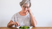 vrouw kijkt vies naar haar bord met eten
