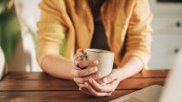 Vrouw drinkt koffie achter  laptop