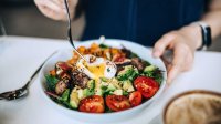 Vrouw eet salade met ei