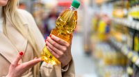 Vrouw in de supermarkt met een fles zonnebloemolie in haar hand