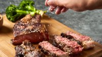 Man bestrooit steak met zout