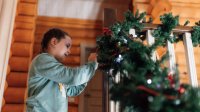 Vrouw is bezig de kerstboom te versieren