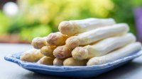 Witte asperges liggend op een blauw bord