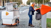 Postbezorger leegt oranje brievenbus