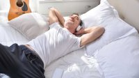 Man ligt op bed met koptelefoon