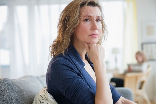 Vrouw zit op de bank kijkt zorgelijk