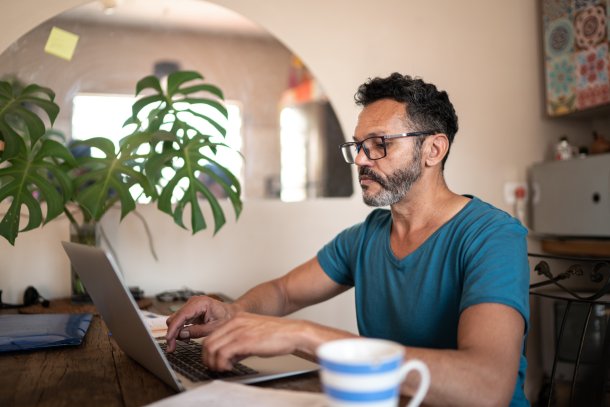 Man is thuis bezig met zijn laptop