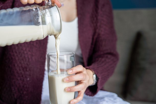 Vrouw schenkt melk in een groot glas