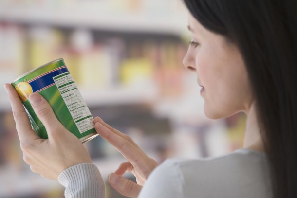 Vrouw leest etiket op een blik in de supermarkt