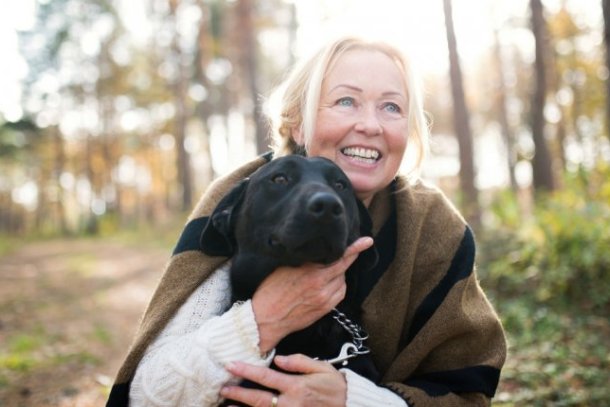 vrolijke vrouw met hond in bos