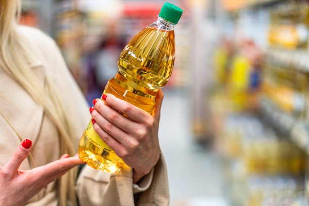 Vrouw in de supermarkt met een fles zonnebloemolie in haar hand