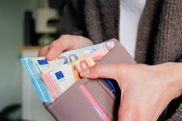 Vrouwelijke hand haalt geld uit portemonnee