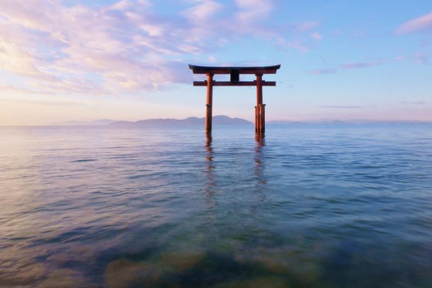 De drijvende Torii-waterpoort in het betoverende Biwameer in Shiga, bij zonsopgang.