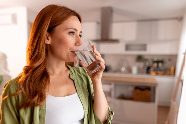 Vrouw drinkt een glas water omdat ze last heeft van de hik