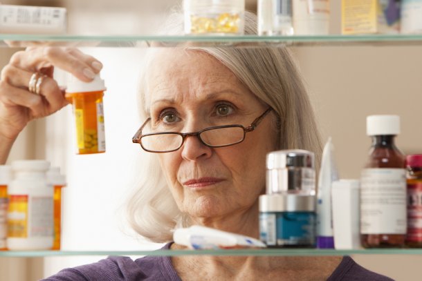 oudere vrouw kijkt in medicijnkastje