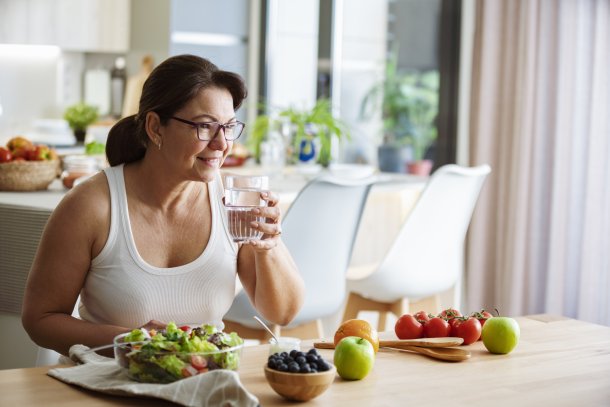 Vrouw eet en drinkt zomer fruit in de keuken