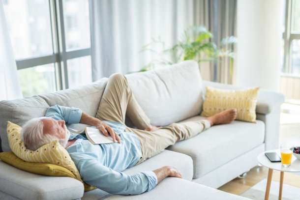 Man doet een dutje in de middag op de bank
