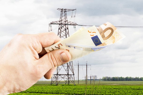 Eurobiljes wordt vastgehouden door mensenhand, energiemast op de achtergrond