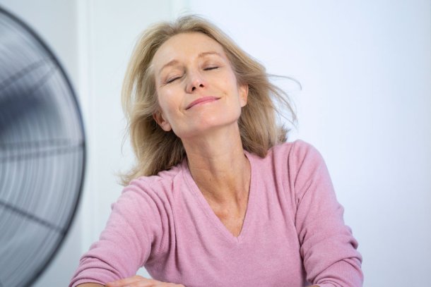Vrouw zit voor ventilator af te koelen