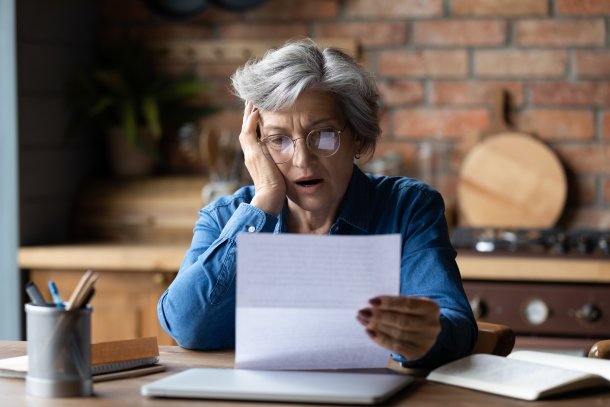 Oudere vrouw leest geschokt een brief
