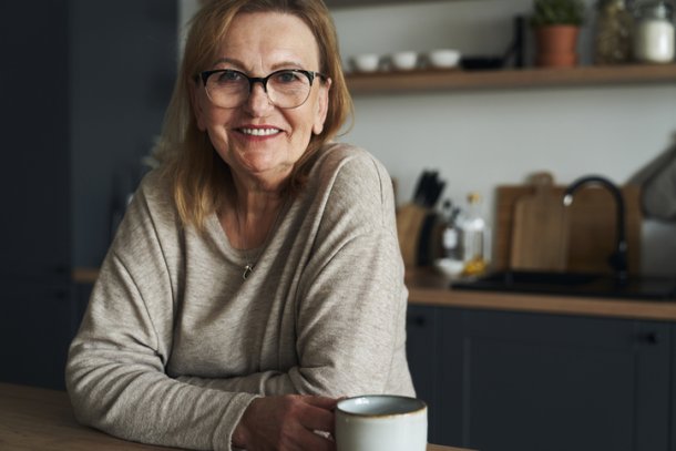 Vrouw leunt op aanrecht in de keuken