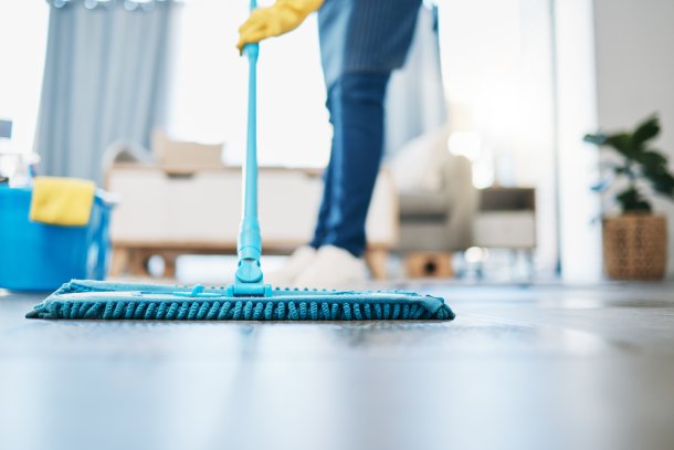 Schoonmaker doet de vloer met een mop