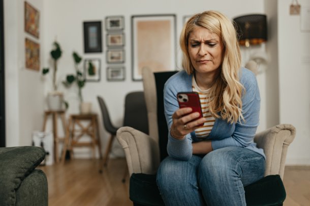 Vrouw is boos, kijkt op haar telefoon in de woonkamer