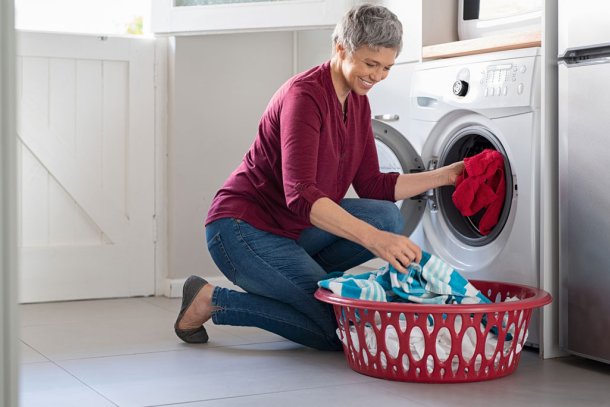 Vrouw doet kleding in de wasmachine