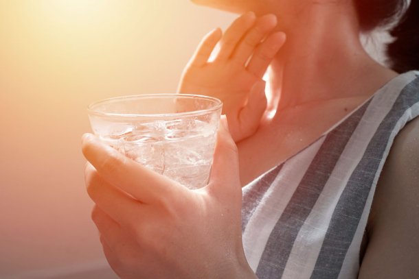Vrouw drinkt glas water met ijsblokjes in de warmte