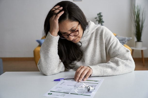 Vrouw bestudeert energierekening met bezorgd gezicht